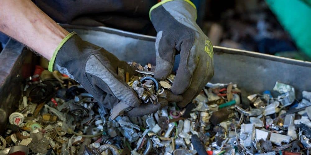 Person sorting metal recyclables by hand.